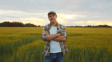 Günbatımı tarımının önündeki çiftçi. Kırsal kesimde bir adam. Kır hayatı, gıda üretimi, tarım ve kırsal yaşam tarzı kavramı.