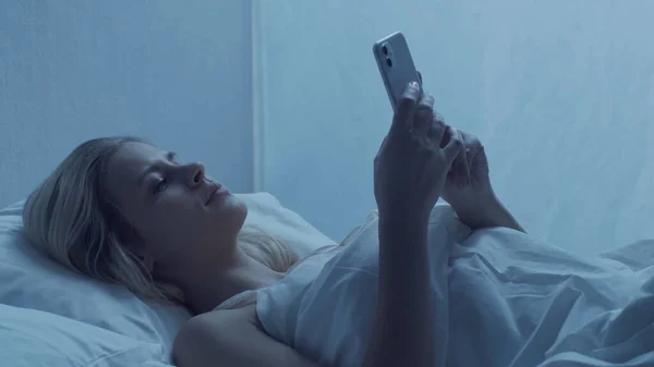 Молодая Женщина Лежит Постели Смартфоном Ночью Красивая Блондинка Отдыхает Сумерки — стоковое фото