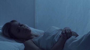 Genç bir kadın gece yatakta yatıyor. Güzel sarışın, uyuyan kız. Yatak odasında alacakaranlık, pencereden ay ışığı. Sağlık ve dinlenme kavramı.