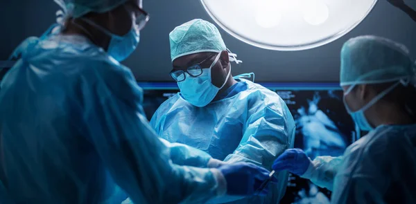 Diverse team of professional medical surgeons perform surgery in the operating room using high-tech equipment. Doctors work to save a patient in a modern hospital. The concept of medicine, technology