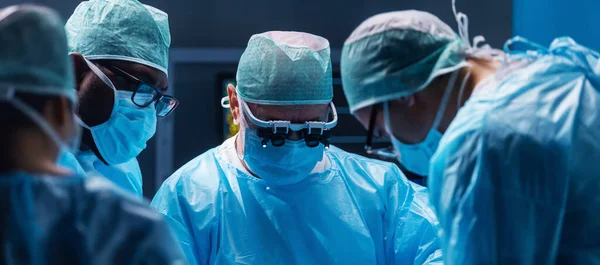 Diverse team of professional medical surgeons perform surgery in the operating room using high-tech equipment. Doctors work to save a patient in a modern hospital. The concept of medicine, technology