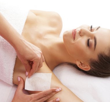 The concept of hair removal, beauty and health. A young girl is getting an epilation procedure. A processional beauty worker is making depilation with hot wax.