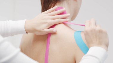 Therapist is applying tape to beautiful female body. Physiotherapy, kinesiology and recovery treatment.