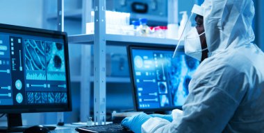 Koruyucu kıyafetli profesyonel Afro-Amerikan doktor modern bir laboratuvarda bilimsel deneyler yapıyor ve aşı geliştiriyor. Laboratuvar asistanı iş yerinde. Bilim ve tıp kavramı.