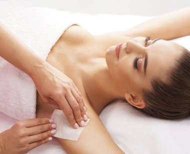 The concept of hair removal, beauty and health. A young girl is getting an epilation procedure. A processional beauty worker is making depilation with hot wax.