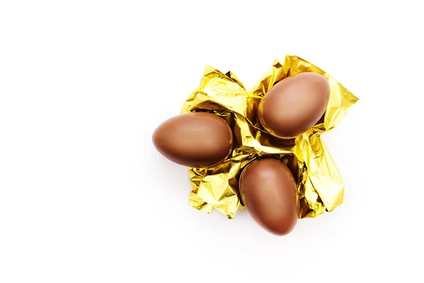 Three chocolate eggs on a golden foil — Stock Photo, Image