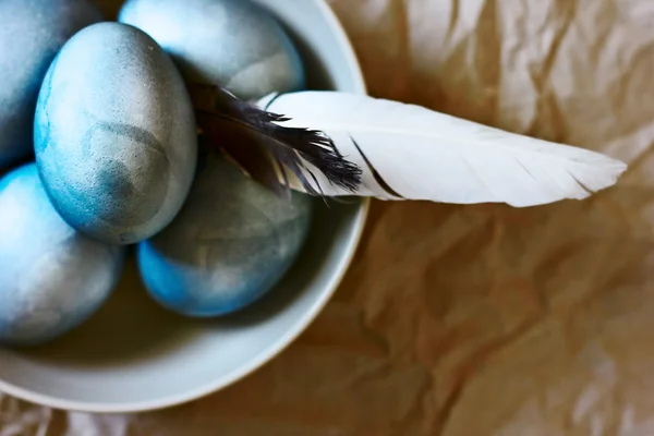 Голубые пасхальные яйца в тарелке с перьями — стоковое фото