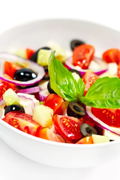 Tasty greek salad with bright vegetables, garnished with basil. — Stock Photo, Image