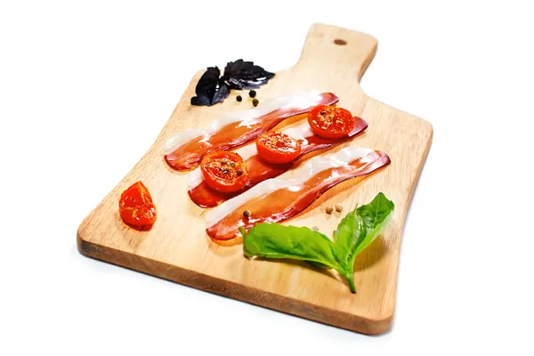 Dried cherry tomatoes with bacon served on carving board. Select — Stock Photo, Image