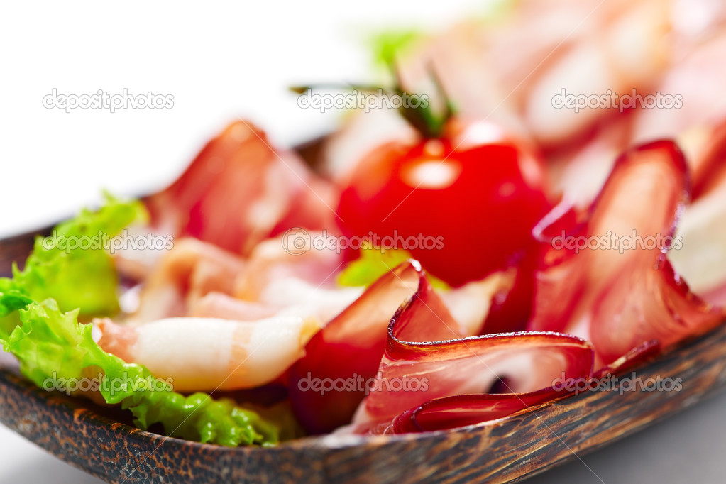 Bacon stripes served with greens and tomato. On white background