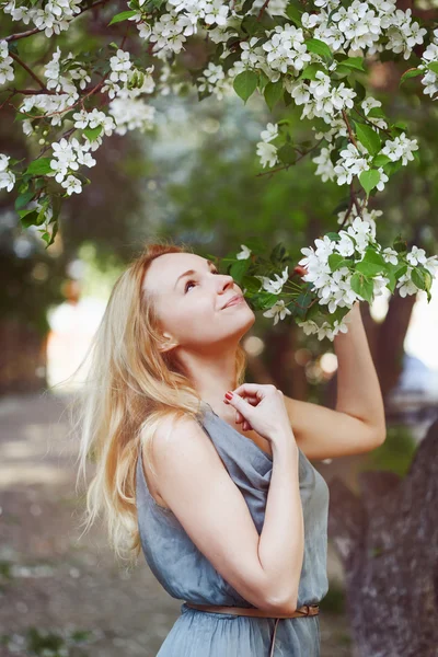 Beautiful young woman is enjoying by spring flowers — Stock Photo, Image