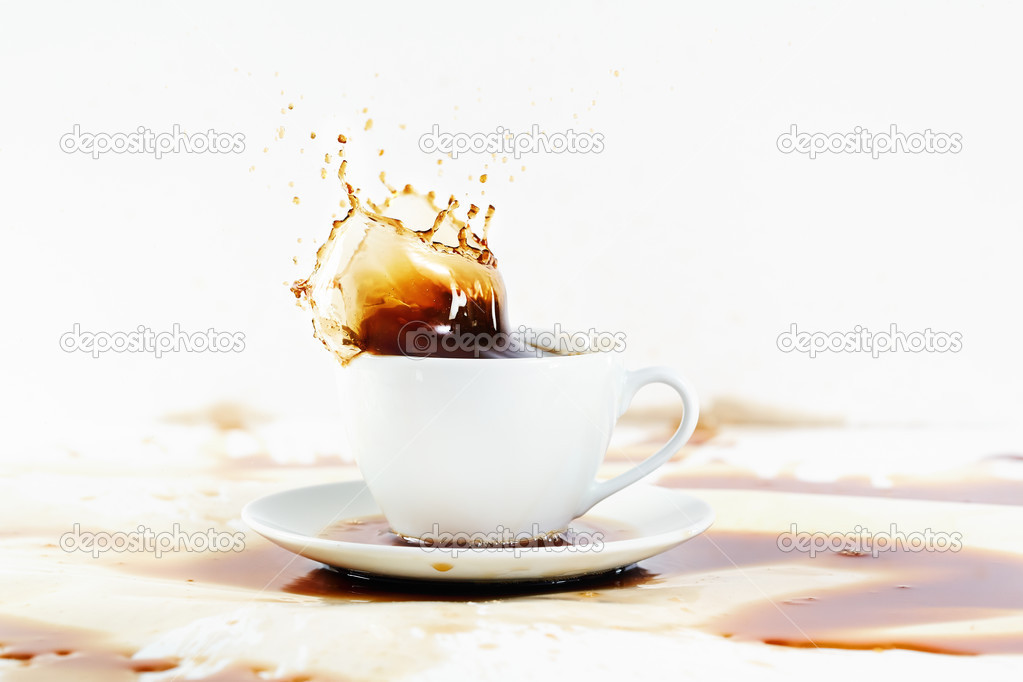 Cup of coffee creating splash. White background, coffee stains.