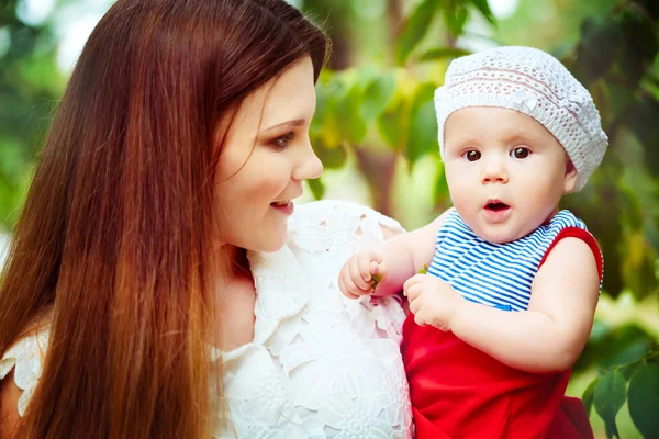 Happy young mother holding baby in park — Stock Photo, Image