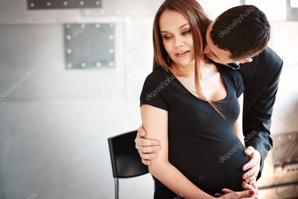 Man kissing his pregnant wife on the neck