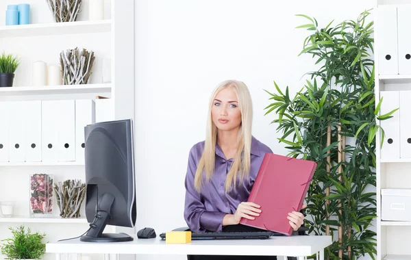 Jonge blonde zakenvrouw met map zit aan de tafel op kantoor — Stockfoto