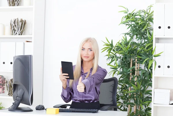 Beautiful girl at office at the computer with reader a thumb up — Stock Photo, Image