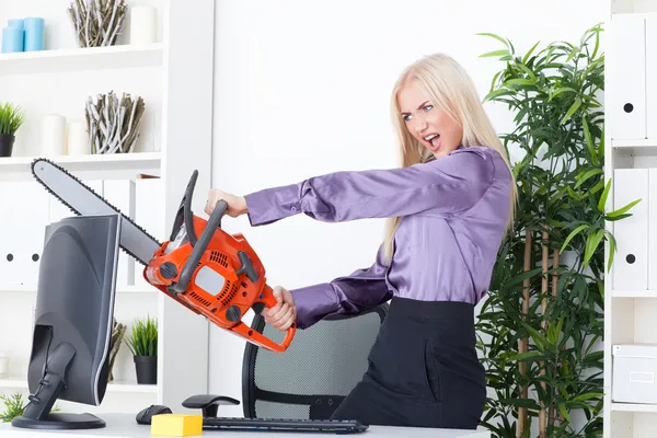 Beautiful girl at the office cuts the monitor with a chainsaw — Stock Photo, Image