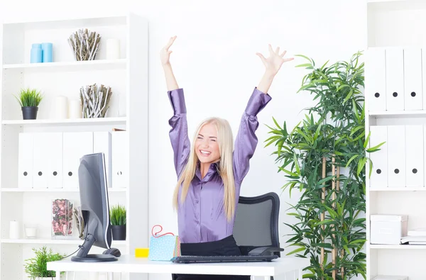 Successful young blonde businesswoman, victory gesture, hands up, smiling at office — Stock Photo, Image