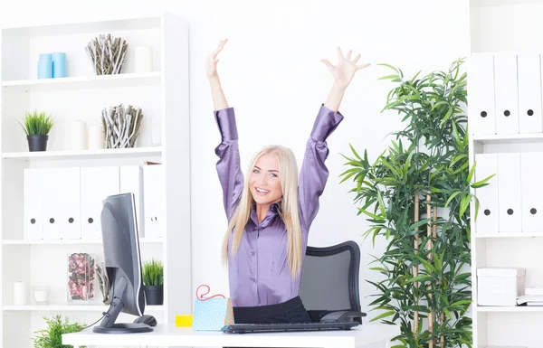 Succesvolle jonge blonde zakenvrouw, overwinning gebaar, handen omhoog, glimlachend op kantoor — Stockfoto