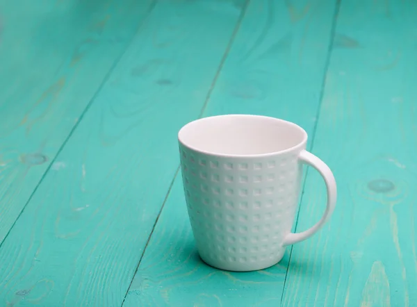 Krásný prázdný bílý šálek na dřevěné tyrkysové pozadí — Stock fotografie