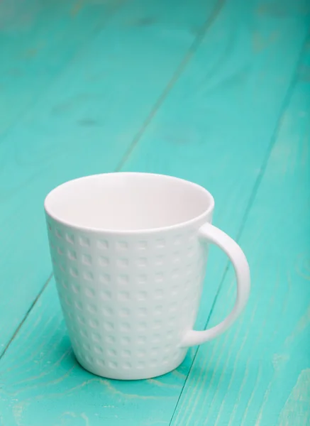 Krásný prázdný bílý šálek na dřevěné tyrkysové pozadí — Stock fotografie