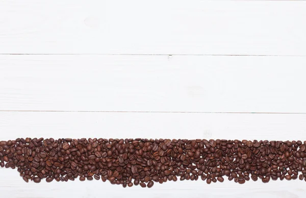 Pannello di legno bianco sfondo con chicchi di caffè — Foto Stock