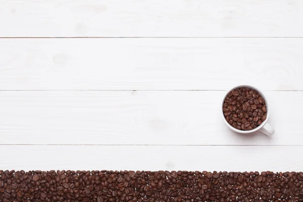 Tavola di legno bianco sfondo con tazza di caffè e fagioli — Foto Stock