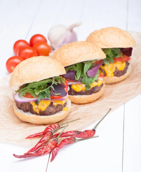 Hamburgers pepper cheese onions sauce tomatoes on paper — Stock Photo, Image