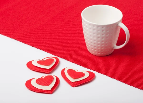 White cup with hearts on a red napkin — Stock Photo, Image