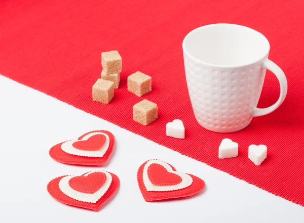 White cup with hearts and sugar on a red napkin — Stock Photo, Image