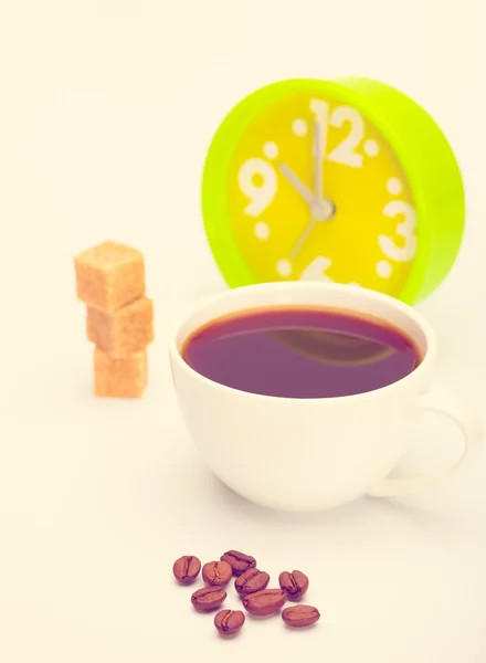 Beautiful white cup, coffee, hearts with an alarm clock on a white background. Toned in warm colors — Stock Photo, Image