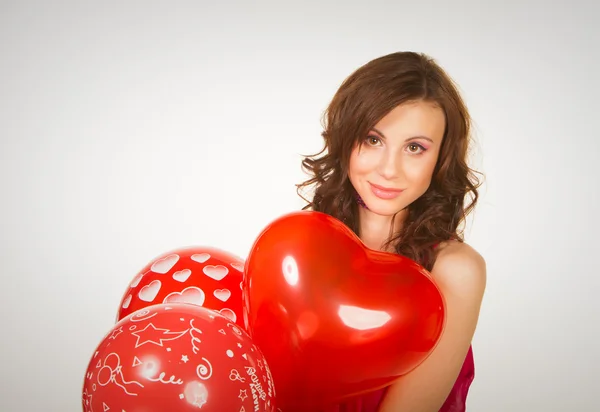 The beautiful brunette in a red dress with balloons — Stock Photo, Image