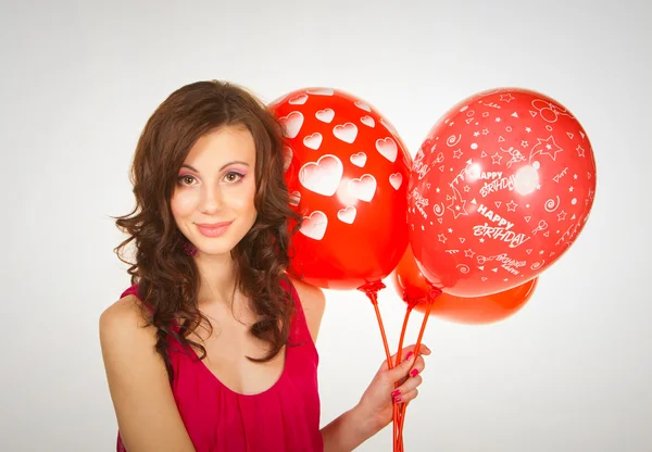 De mooie brunette in een rode jurk met ballonnen — Stockfoto