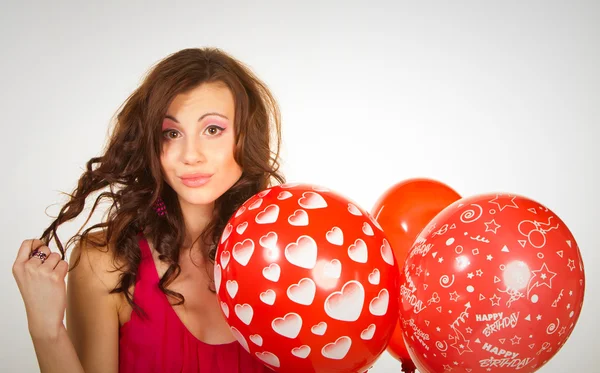 De mooie brunette in een rode jurk met ballonnen — Stockfoto