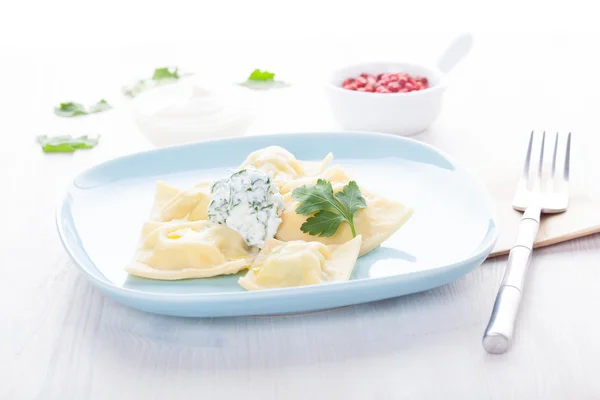 Homemade ravioli on a blue plate with sauce and seasonings — Stock Photo, Image