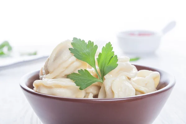 Pelmeni appetitosi in una ciotola marrone con salsa e spezie — Foto Stock