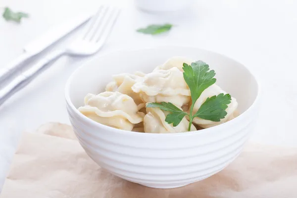 Appetizing pelmeni in a beautiful white bowl with sauce and spices — Stock Photo, Image