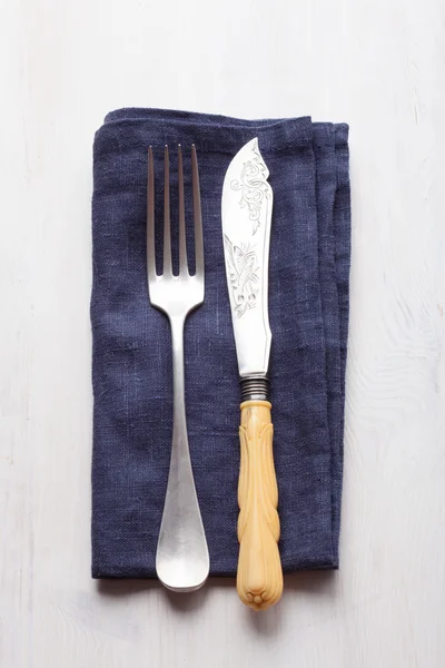 Vintage fork and knife a blue napkin on a vintage wooden board — Stock Photo, Image