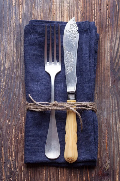 Vintage fork and knife a blue napkin on a vintage wooden board — Stock Photo, Image