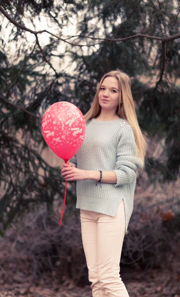 El retrato abierto de la mujer joven la mujer hermosa en el tiempo frío en el parque. La sensual rubia posa y es alegre con un globo rojo . —  Fotos de Stock