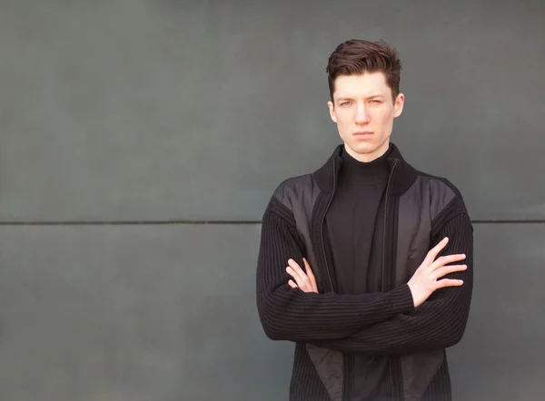Model młody człowiek w czarną kurtkę stawia na ścianie — Zdjęcie stockowe