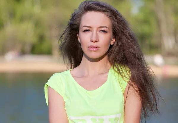 Beautiful Fitness the model in a Top Costs on the bank of the Lake in the Summer on a sunset. Blowing Long Hair — Stock Photo, Image