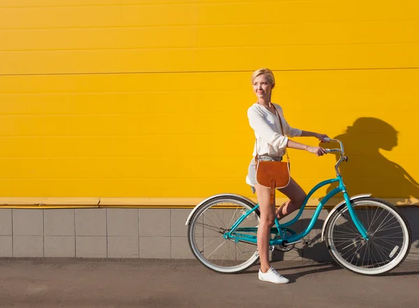Menina loira sexy nova está de pé perto da bicicleta verde vintage com saco vintage marrom Fotografia De Stock