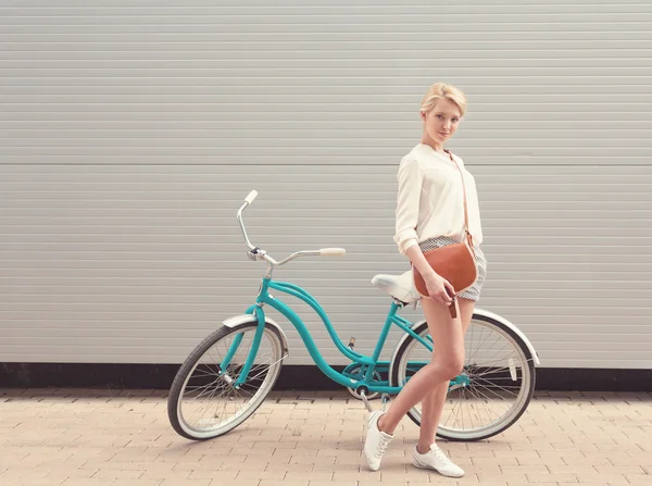 Vacker blond flicka står nära vintage cykel med brun vintage väska ha kul och gott humör titta i kameran och leende, varm, Tönning — Stockfoto