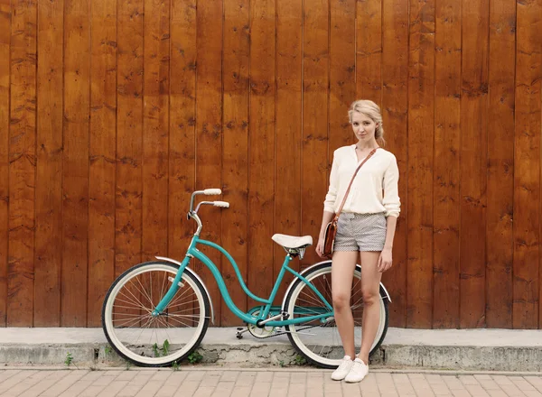 Giovane ragazza bionda sexy con i capelli lunghi in piedi vicino bicicletta verde vintage hanno divertimento e buon umore guardando in macchina fotografica e sorridente, caldo, tonificante — Foto Stock
