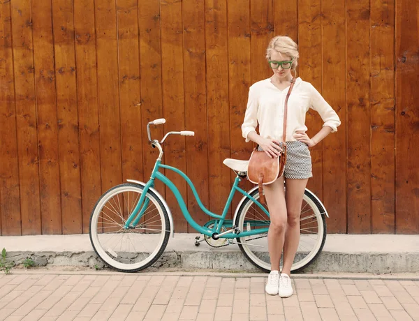 Jeune fille blonde sexy se tient près du vélo vert vintage avec sac vintage brun en lunettes de soleil vertes, chaud, tonning — Photo