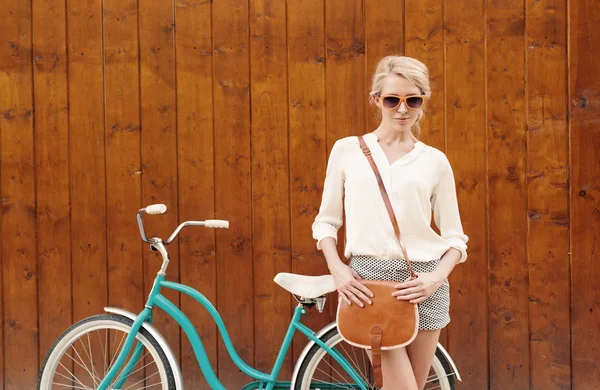 Junges sexy blondes Mädchen steht neben dem grünen Vintage-Fahrrad mit brauner Vintage-Tasche in orangefarbener Sonnenbrille, warm, tönend — Stockfoto