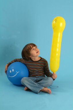 üzerinde mavi renkli balonlar ile mutlu çocuk