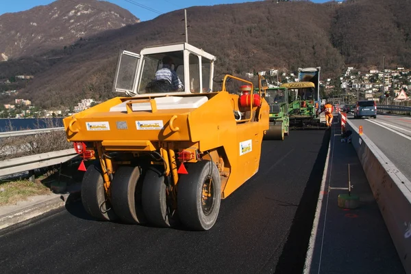 Camiones de mezcla de asfalto construyendo una carretera — Foto de Stock