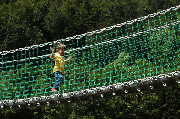 Un joven camina sobre un puente colgante —  Fotos de Stock